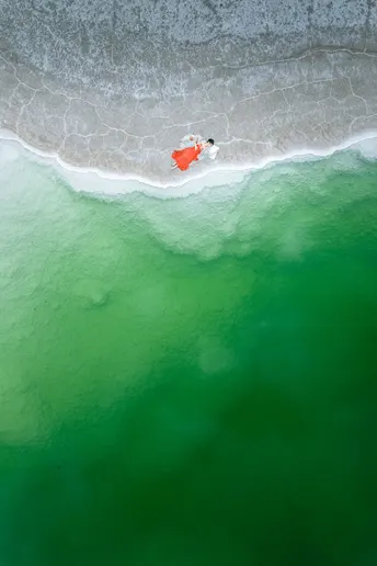 海上的一张沙滩照片 人们在水里游泳 一艘船在海洋中。