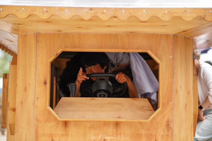 一个带着相机的男人在一个木制狗屋中拍照