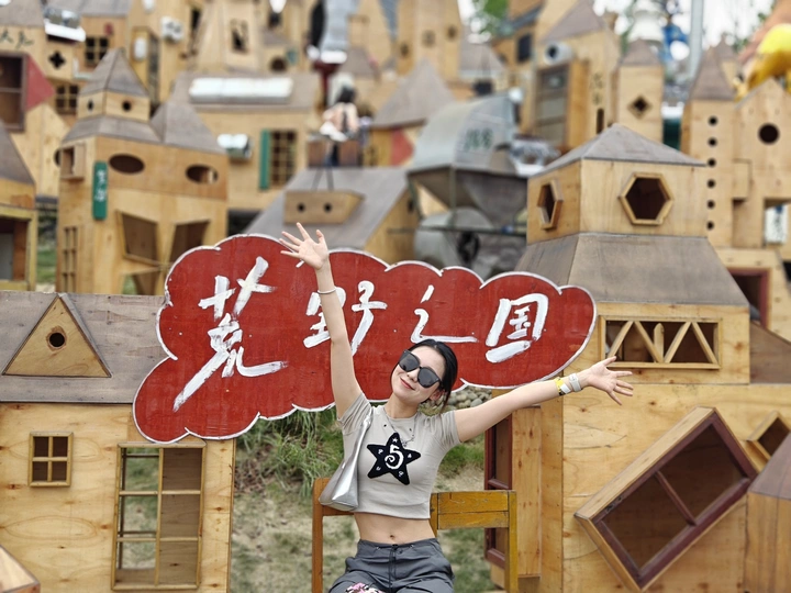 一位年轻女子在木质房屋堆前拍照