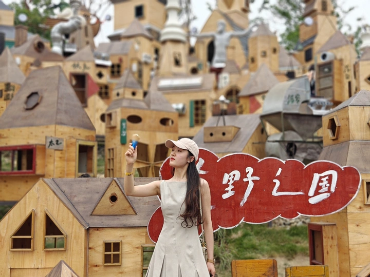 一位穿着连衣裙的年轻女子在木质房屋前的村庄中为拍照姿势。