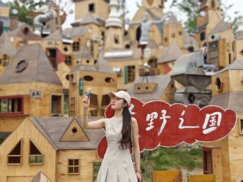 一位穿着连衣裙的年轻女子在木质房屋前的村庄中为拍照姿势。