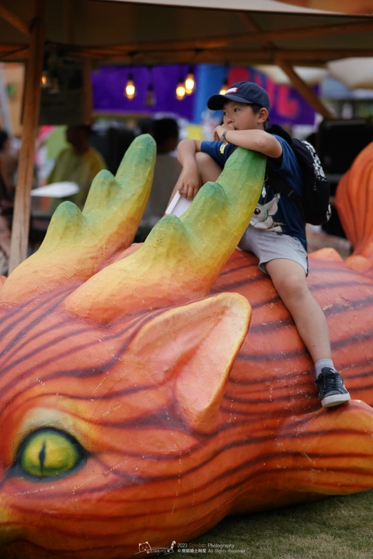 一个小孩子站在一个大的假南瓜上 手上坐着一个手。