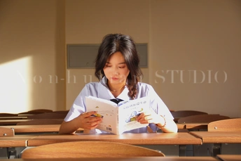 一个年轻女孩坐在教室的桌子旁读书