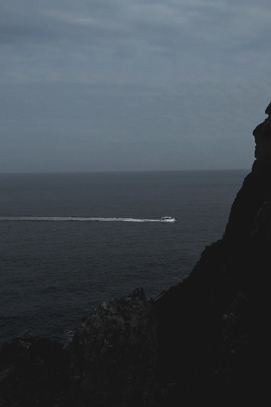 一艘在岩石悬崖海岸外航行的船
