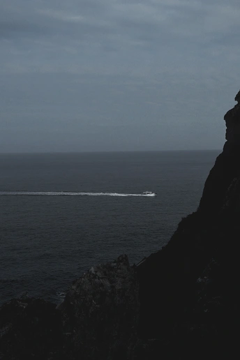 一艘在岩石悬崖海岸外航行的船