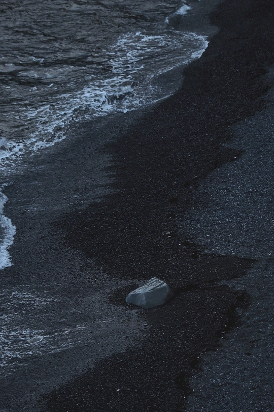 夜晚海滩上有瓶子在水中漂浮 岸边有岩石。