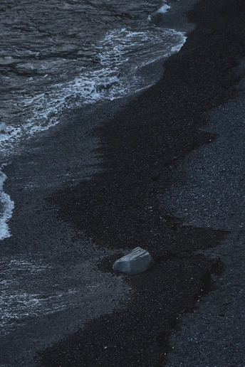 夜晚海滩上有瓶子在水中漂浮 岸边有岩石。