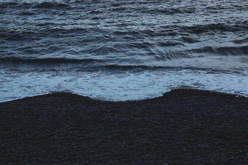 夜晚的黑沙滩 海浪拍打着沙滩 月亮在天空中。