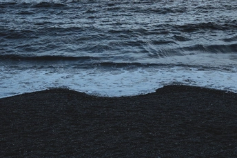 夜晚的黑沙滩 海浪拍打着沙滩 月亮在天空中。