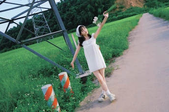 一位穿着白色连衣裙的年轻女子站在一条路上