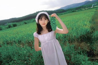 一位穿着白裙子的女孩在绿色的原野上