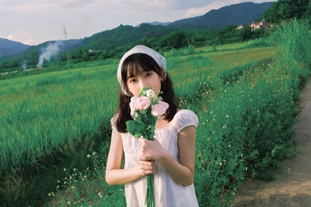 一个小女孩穿着裙子 拿着粉红色玫瑰。