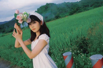 一位穿着白色连衣裙和帽子 手里拿着花的年轻女子