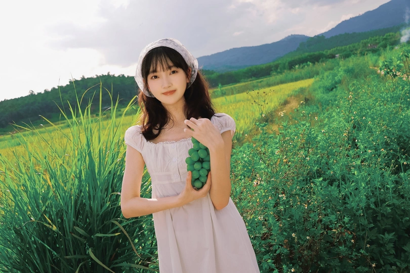 一位穿着白色连衣裙站在绿色原野上的女人