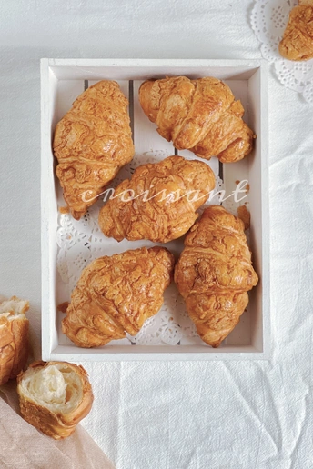 一个方形的白色盒子 里面装着羊角面包和其他糕点