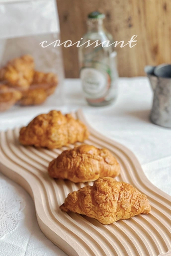 一些羊角面包放在桌子上的木托盘上