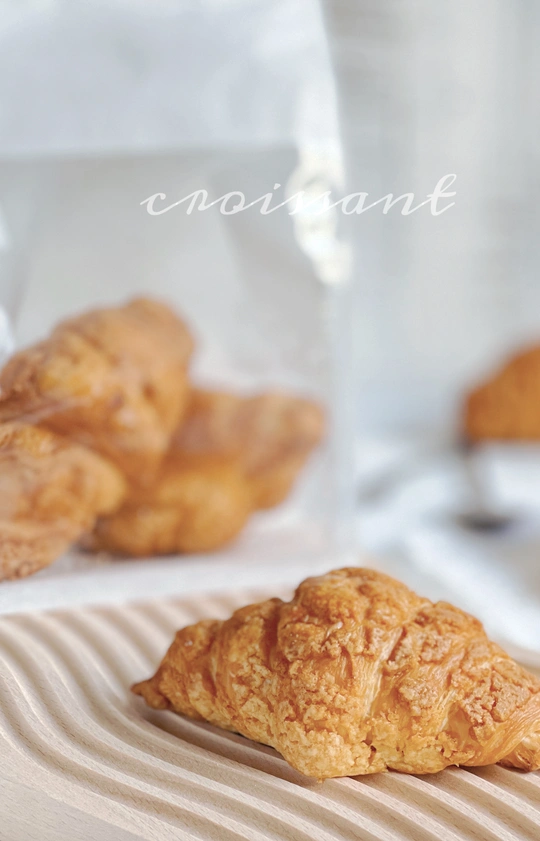 一些放在白色盘子里的羊角面包和一袋咖啡