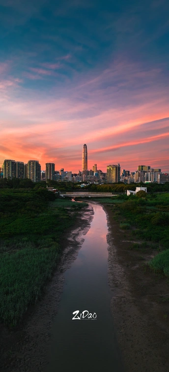 夕阳下的城市 背景是天际线 前景是水面。