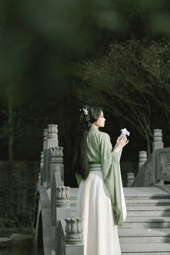 一位穿着绿色和白色连衣裙站在楼梯上的女人