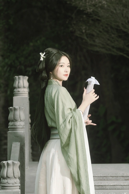 一位穿着传统白色连衣裙的年轻女子手里拿着一把雨伞