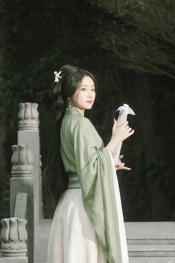 一位穿着传统白色连衣裙的年轻女子手里拿着一把雨伞