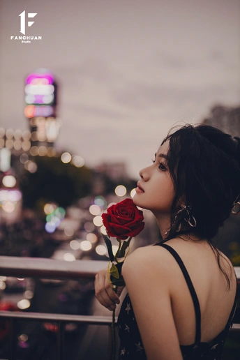 一位女士在阳台上拿着一朵红玫瑰 俯瞰城市