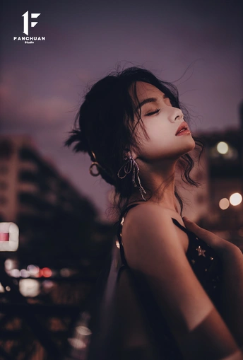 一位年轻女子夜晚站在屋顶上闭着眼睛