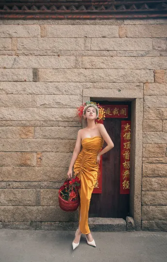 一位穿着黄色连衣裙的女人站在一个有红色篮子的墙壁前