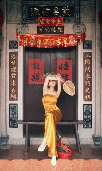 一位穿着黄色的女人坐在门前的一张长凳上