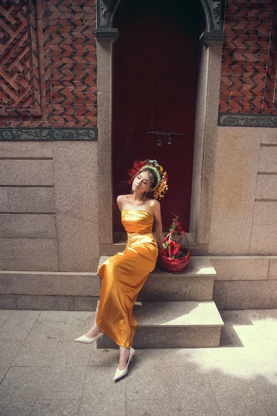 一个穿着黄色连衣裙的美女在建筑物的台阶上摆姿势
