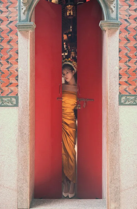 一个穿着长袍的年轻女孩站在一座寺庙的门口