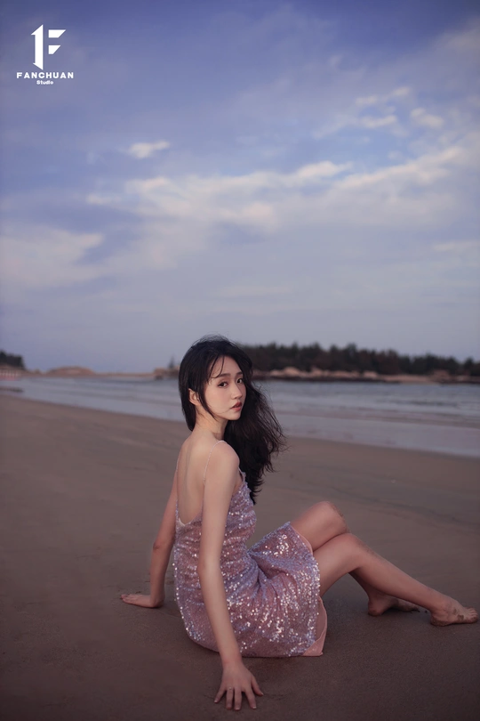 一位穿着漂亮裙子的年轻女子坐在海滩上