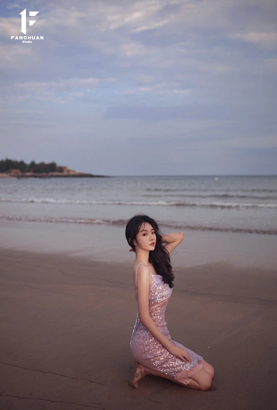 一位穿着漂亮裙子的年轻女子在海滩上跪在沙子里