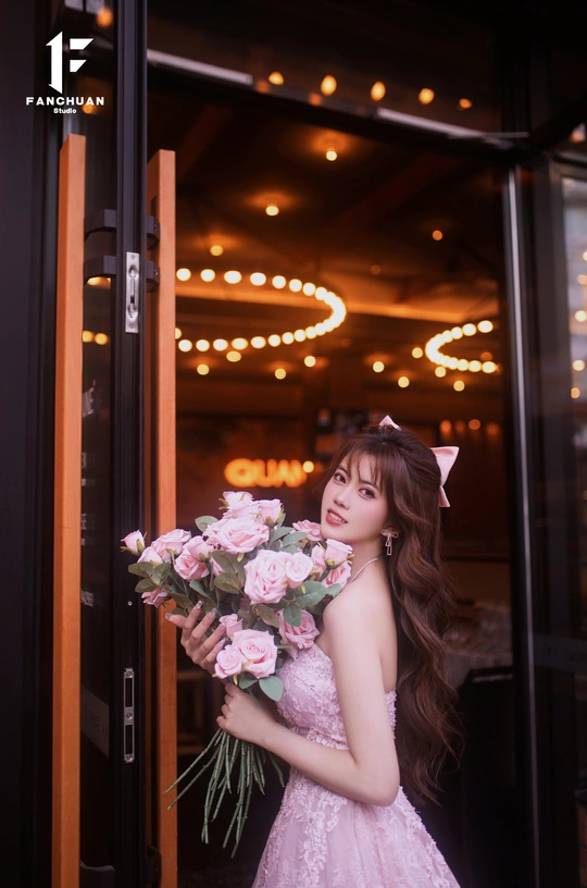 一个穿着粉红色连衣裙的年轻女子 手里拿着一束花 站在门前。