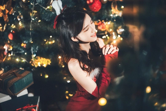 站在圣诞树前的穿红裙子的年轻女子