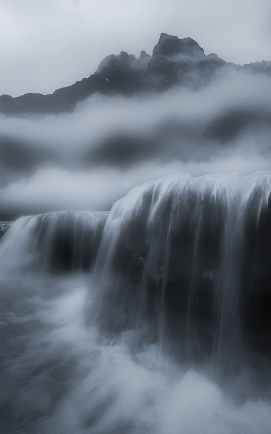 瀑布在山脉中的长曝光 有雾和云