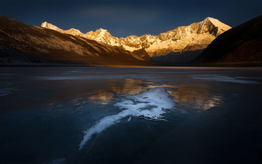冰封的湖面反射出落日时分山峦的阳光。