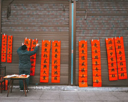 站在挂着红灯笼的墙前的男子