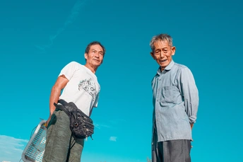 几个年长的男人站在一个场地上 带着滑板。