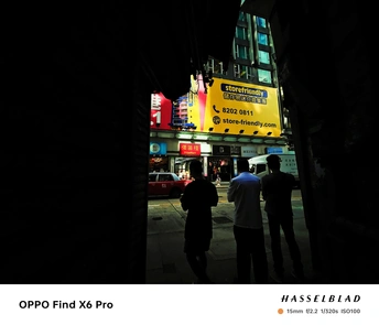 夜晚的城市街道 人们站在街道上 建筑物上有一个黄色标志。