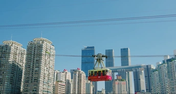 空中飞行的红色缆车在城市高楼上空