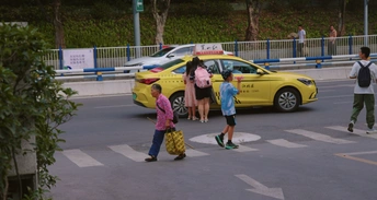 几个人穿过街道 带着滑板和背景中的黄色出租车。