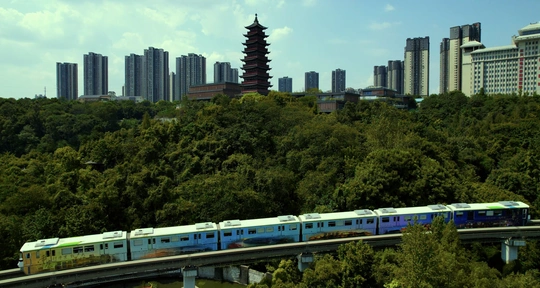 一艘蓝色和白色的火车穿越一座桥 背景是大型建筑的城市天际线。