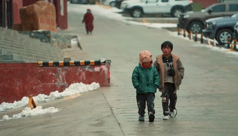 一个男子和一个年轻男孩走在一条人行道上 靠近一条公路。