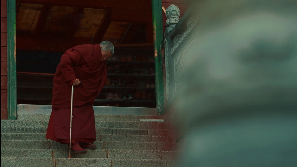 一个穿着红袍的老人 手拿拐杖 正在走上楼梯。