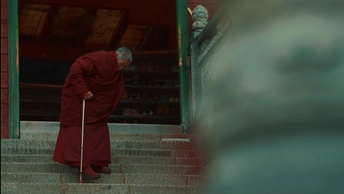 一个穿着红袍的老人 手拿拐杖 正在走上楼梯。