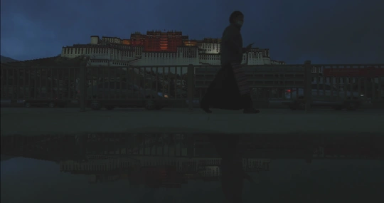 一个人和一个女人在夜晚沿着水边走 背景中有建筑物。