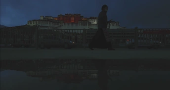 一个人和一个女人在夜晚沿着水边走 背景中有建筑物。