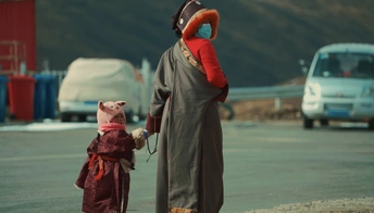 一个穿着恶魔服装的女人在停车场里握着孩子的手。