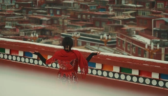 一张中国城市中 一位穿红衣服的女士站在阳台上 俯瞰着建筑的屋顶。